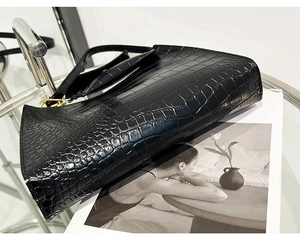 Detail of black stone pattern shoulder bag showing glossy texture and gold metal hooks