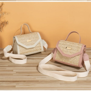 Detail view of woven straw crossbody bags with metal buckle and fabric shoulder straps