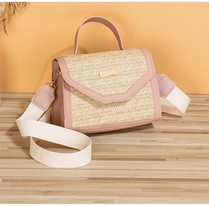 Detail view of pink leather and woven straw crossbody bag with golden metal buckle