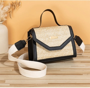 Detail of straw woven bag with black leather trim and gold geometric metal buckle