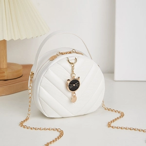 White quilted round crossbody bag with golden chain and cute black cat charm accessory