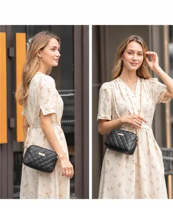 Detail van zwarte gewatteerde crossbodytas met gouden metalen plaat en ketting