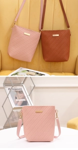 Detail of woven texture bucket bag with gold metal plate and adjustable strap