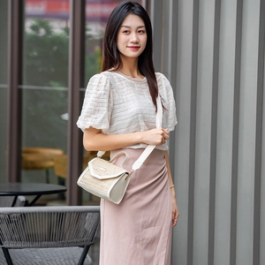 Women's trendy straw crossbody bag with sequins and wide shoulder strap in outdoor setting