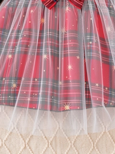 Detalle del vestido de cuadros rojos y negros con tul de estrellas doradas y lazo