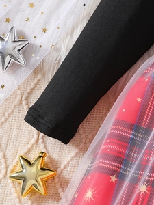 Detalle de vestido para niña con mangas negras y cuadros rojos con tul de estrellas