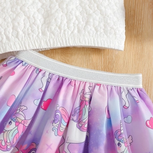 Détail d'une jupe tutu arc-en-ciel pour fille avec motifs licorne et haut blanc texturé