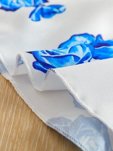 Close-up of fine overlock stitching on white fabric with blue rose print texture