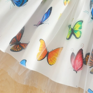 Detail of multi-colored butterfly prints on layered white tulle and mesh skirt fabric