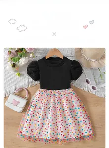 Detail of girl's summer dress with black ribbed bodice and colorful polka dot mesh skirt