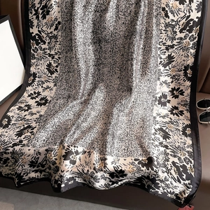 Elegant floral silk satin scarf with black and white patterns and soft draped texture