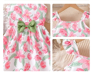 Détails d'une robe fleurie pour fille avec nœud vert et bretelles à volants
