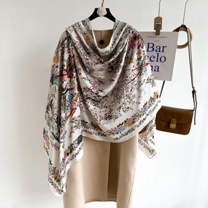 Floral satin silk scarf with white background elegantly draped over a beige coat