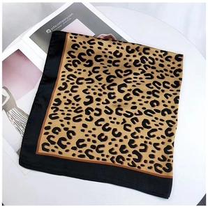 Flat lay of a leopard print silk scarf with black border on a white table and magazine