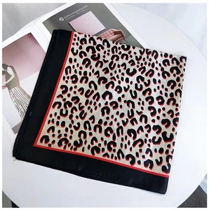 Detailed view of square leopard print silk scarf with black red spots and contrast border