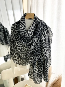 Close-up of leopard print scarf fabric showing soft texture and elegant draped layers