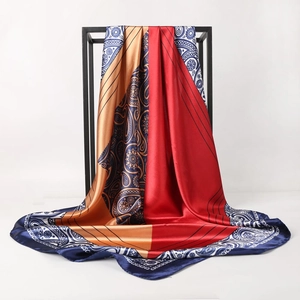 Vintage paisley print silk scarf in red and gold displayed on a minimalist metal stand