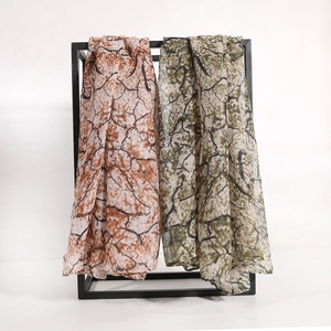 Lightweight mosaic print long scarf in red and olive green on a minimalist metal stand