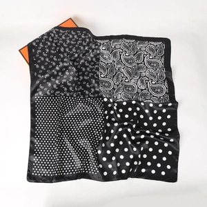 Carré en soie avec motifs à pois et paisley noir et blanc sur un coffret orange