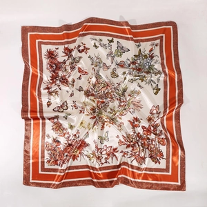 Detail of green and orange butterfly floral print satin silk square scarf showing texture