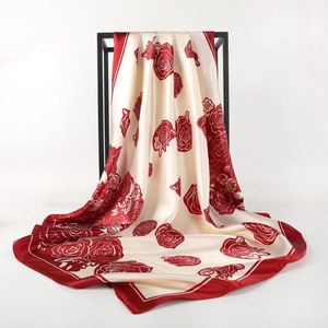 Elegant off-white silk scarf with red rose prints hanging on a minimal black metal rack