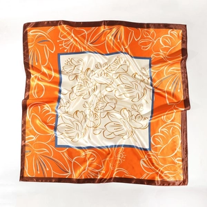 Detailed pattern of a 90cm satin square scarf with orange floral prints and silk texture