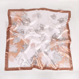 Detailed close-up of white satin square scarf featuring golden floral chrysanthemum patterns