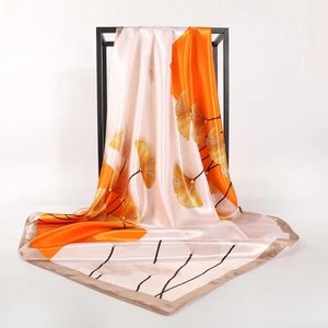 Elegant ginkgo leaf print satin scarf displayed on a black frame with smooth drape