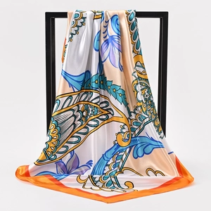 Zijden vierkante sjaal met paisley print in oranje en blauw op een metalen standaard