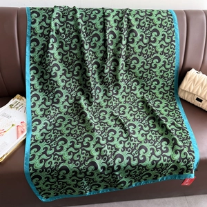 Elegant vintage black and green paisley silk scarf draped over a leather sofa