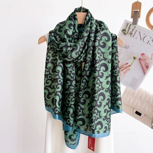 Silky vintage black and gold scarf with whirlpool patterns draped on a wooden hanger