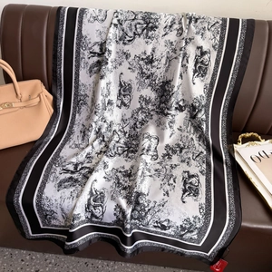 Seidenschal mit schwarz-weißem Toile-de-Jouy-Druck auf einem braunen Ledersofa