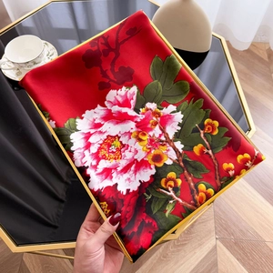 Detail view of red silk scarf featuring elegant peony patterns and smooth satin texture