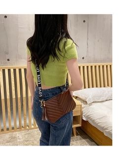 Détail du sac bandoulière en cuir marron matelassé en V avec franges et sangle LOVE