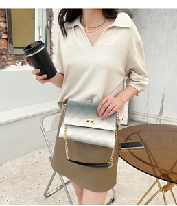 Detail of gradient quilted chain bag with gold twist lock on a minimalist cafe table