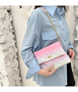Detail of pink gradient quilted crossbody bag with gold chain strap worn by a model