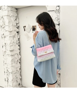 Detail of pink and white gradient quilted shoulder bag with gold chain strap on model