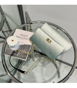 Detail of green gradient quilted crossbody bag with gold lock and chain strap on glass table