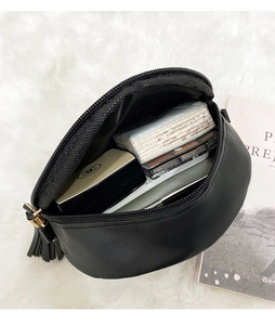 Internal view of black PU leather crossbody bag showing daily essentials and tassel detail