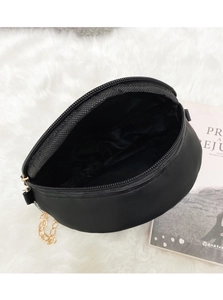 Top view of open circular PU leather crossbody bag with gold chain and black lining