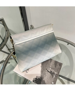 Close-up of a gradient quilted chain crossbody bag with golden hardware on a table