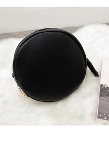 Detail of round black crossbody bag featuring gold chain and long leather tassel