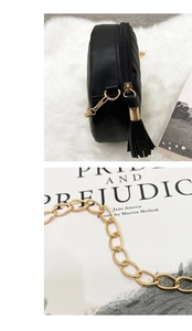 Detail of black quilted round bag featuring golden chain strap and tassel zipper puller