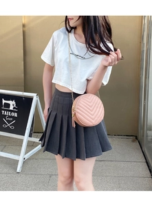 Pink quilted round crossbody bag with fringe tassel and gold chain strap on female model