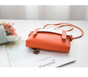 Détail du sac bandoulière orange et blanc avec texture litchi et rivets dorés