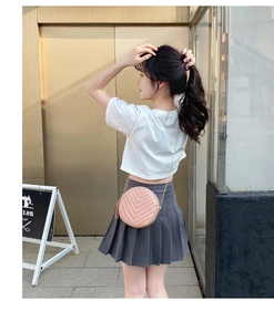 Pink round quilted crossbody bag with golden chain and tassel detail on street model