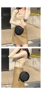Detail of black quilted round crossbody bag with gold chain strap and stylish tassel