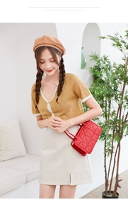 Detail of red quilted crossbody bag with golden chain strap and top handle