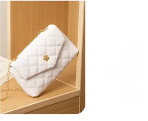 Close-up of white quilted crossbody bag featuring golden camellia metal buckle and chain