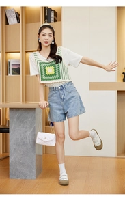 Chic white quilted crossbody chain bag paired with green crochet vest and denim shorts
